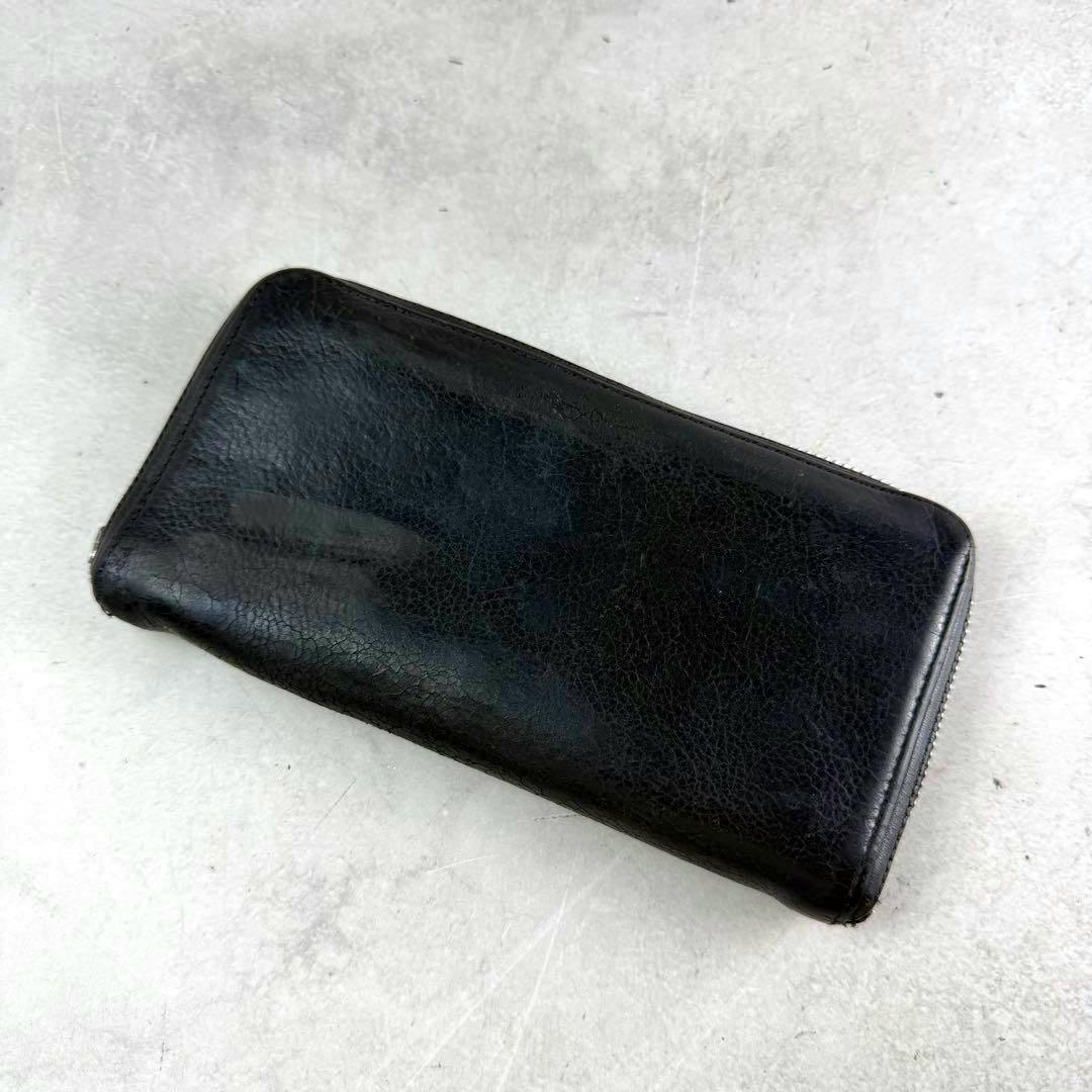 Black cow-leather long zip-around wallet shown on a light textured background, displaying the exterior surface.