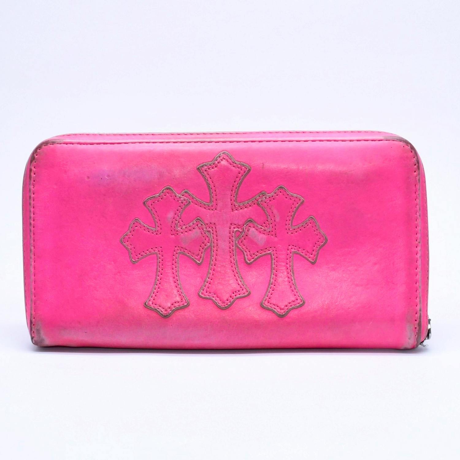 Front view of a pink cow leather long wallet with three stitched cross patches and visible wear.