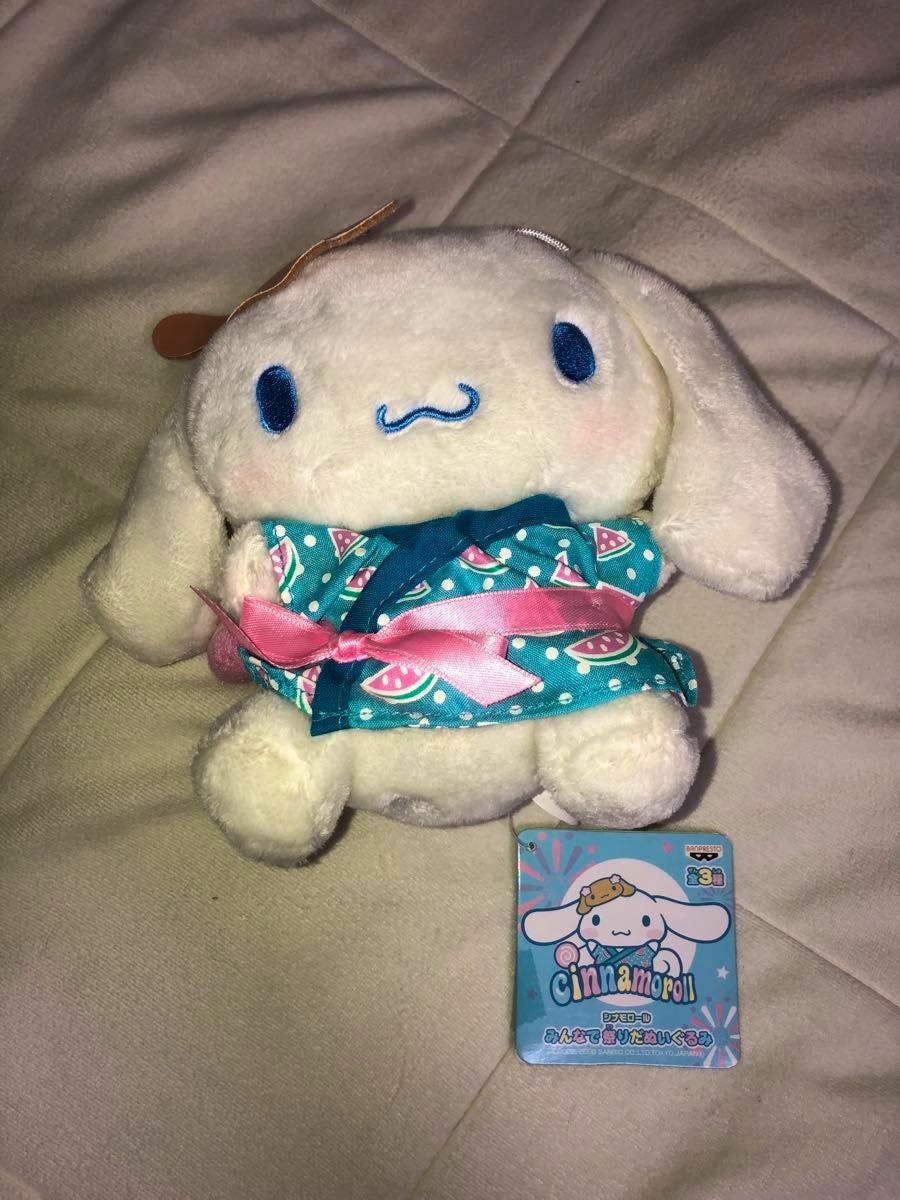 Front view of the white Cinnamoroll plush toy wearing a teal patterned festival outfit with a pink ribbon and its tag visible.