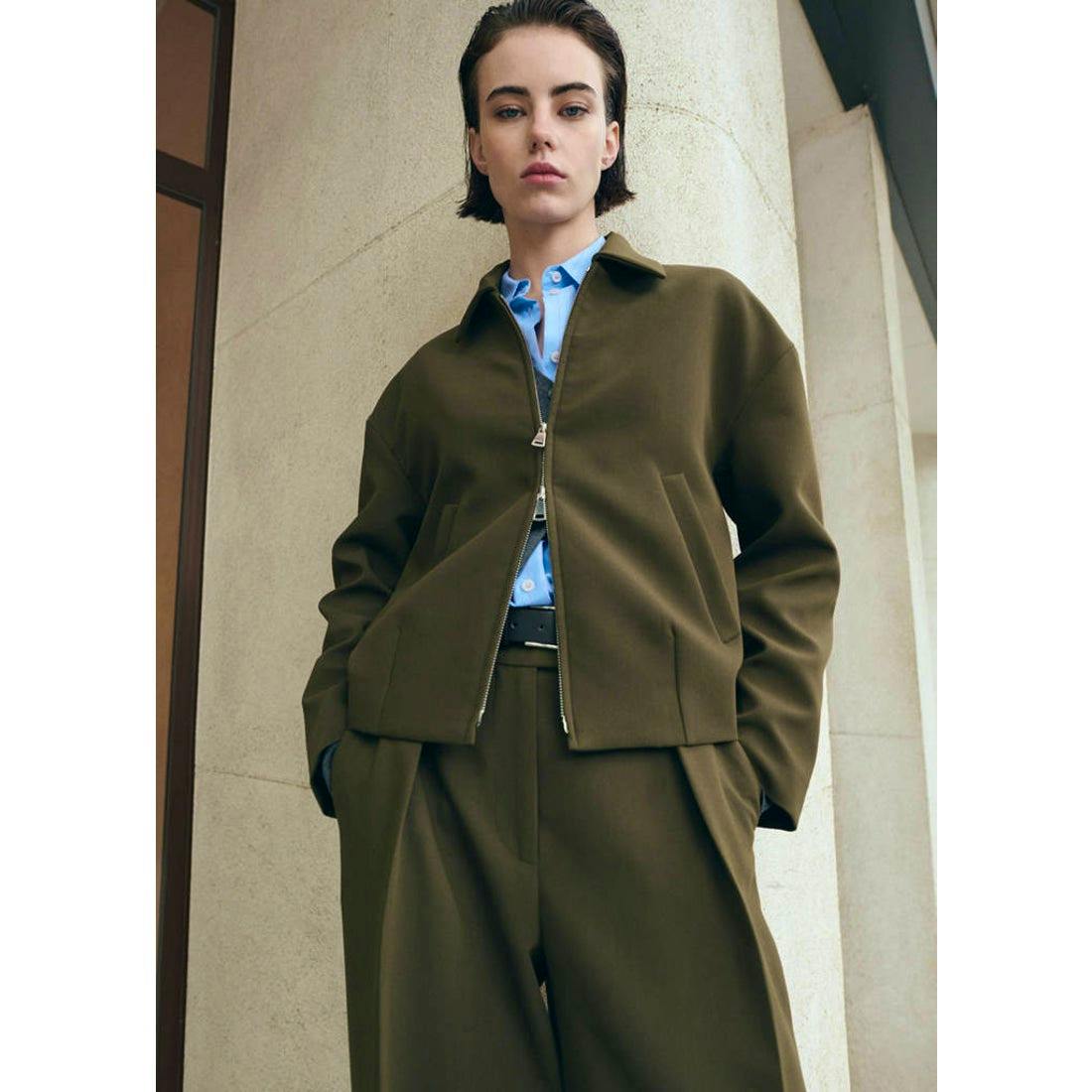 Front view of a khaki women's jacket worn by a model, showing the zipper and front pockets.