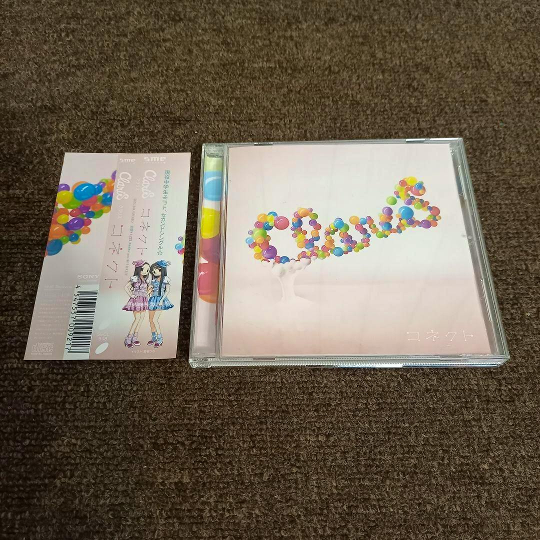 A photographed CD case for 【美品】コネクト　ClariS showing the cover art of colorful balloon-like spheres, with a separate paper obi/inlay placed beside it on a carpeted surface.