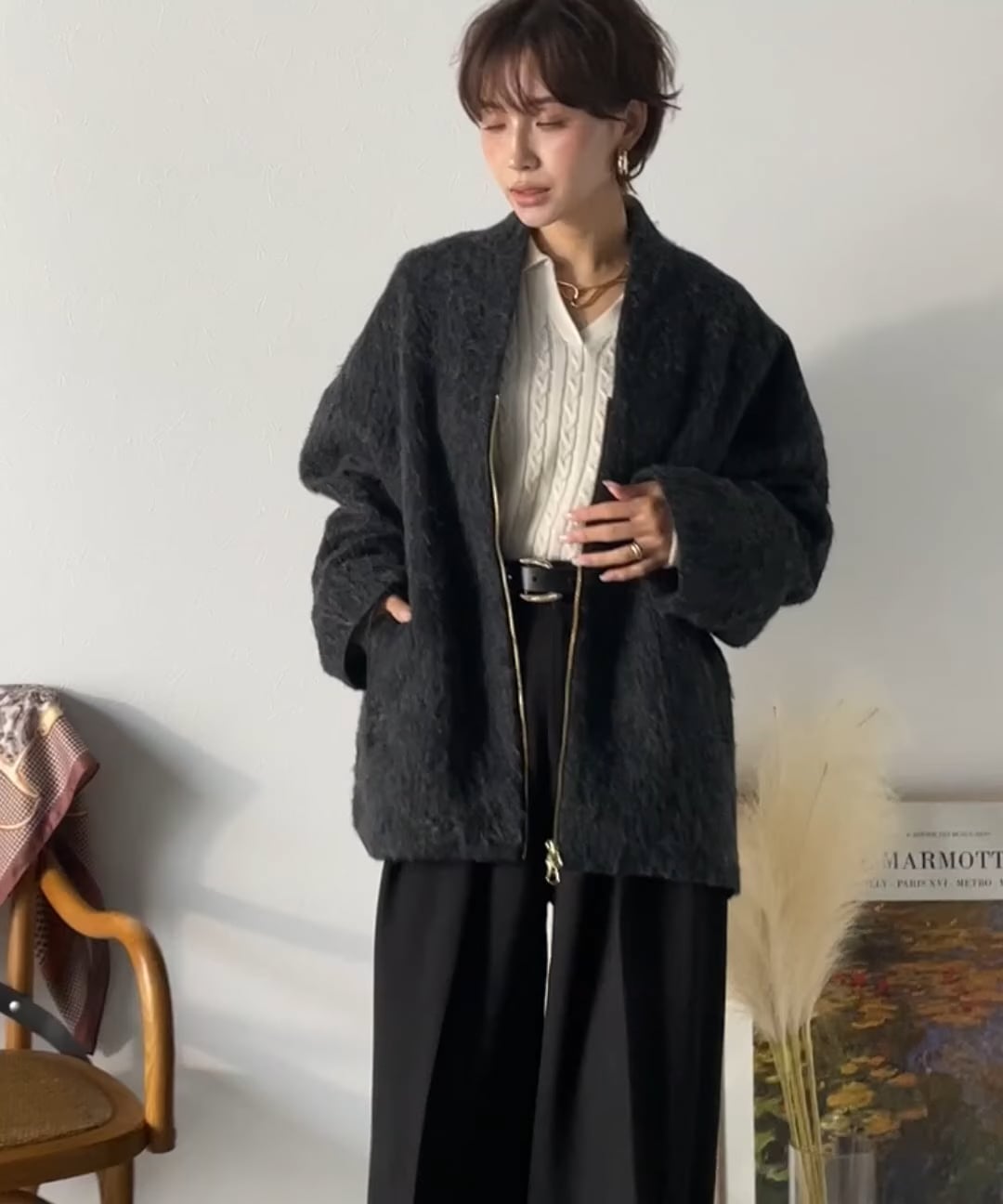 Model wearing a dark shaggy no-collar women's coat with zipper and pockets.