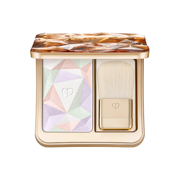 Gold compact blush palette showing a multicolored geometric pressed powder and a small brush inside.