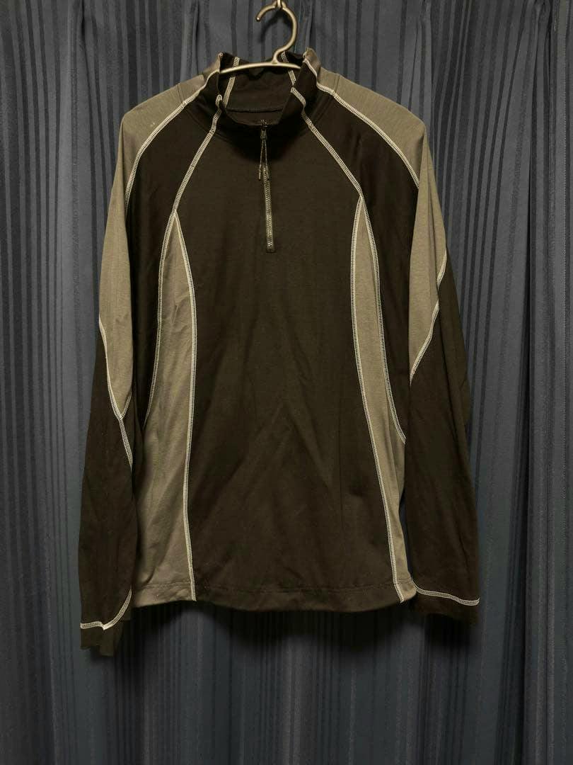 Long black and gray long-sleeve T-shirt with contrast white stitching and a short front zipper hanging on a hanger.