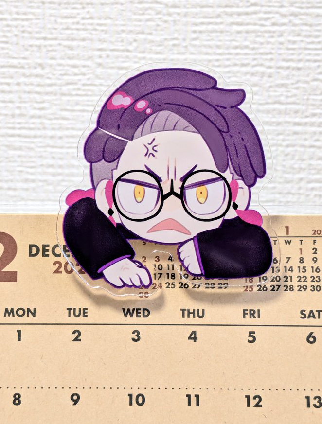 A decorative hair clip shaped like a chibi character clinging to the edge of a calendar.