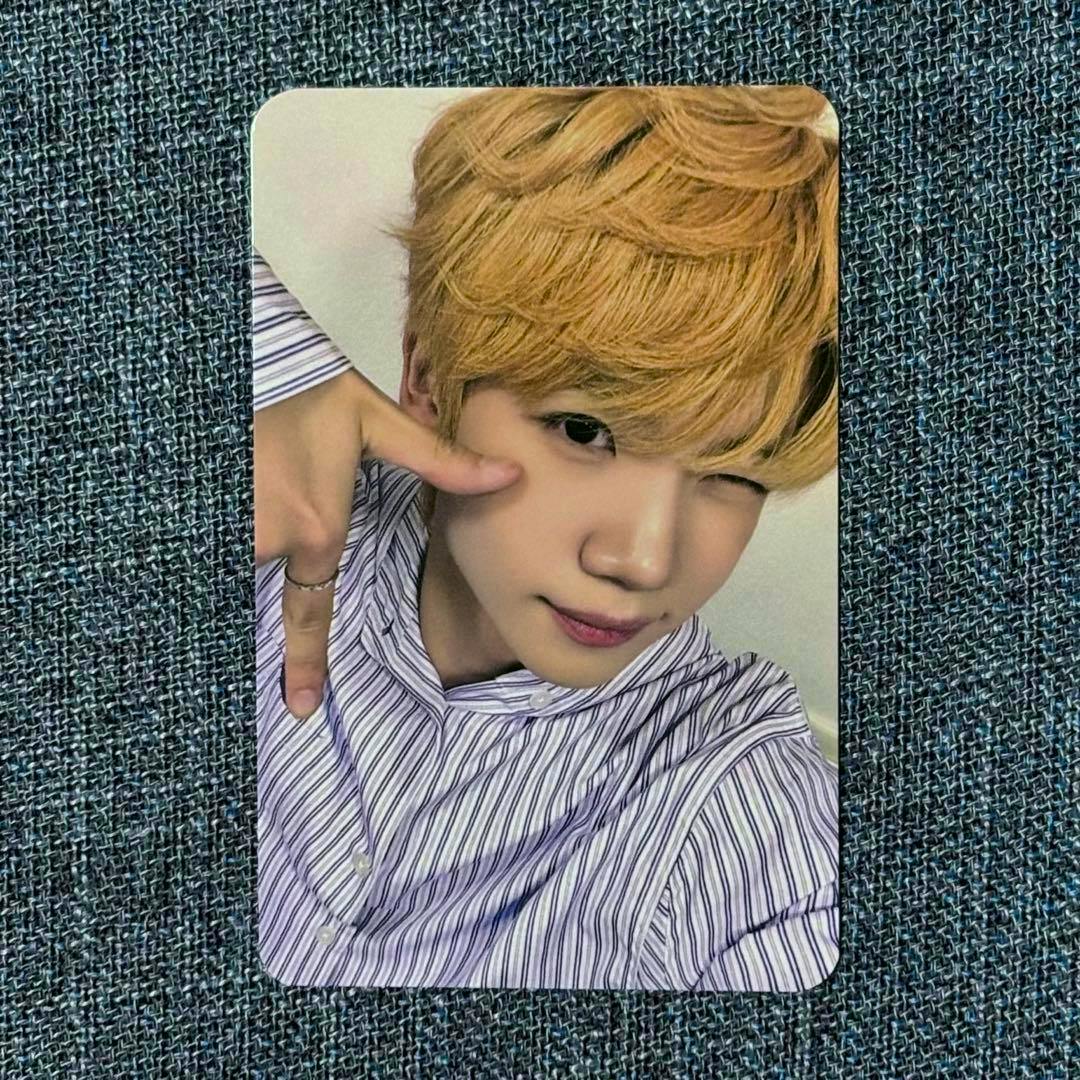 Photocard for "CLOSE YOUR EYES ケンシン ヨントン トレカ" showing a person with blond hair winking and making a hand gesture while wearing a striped shirt on a blue-gray textured background.