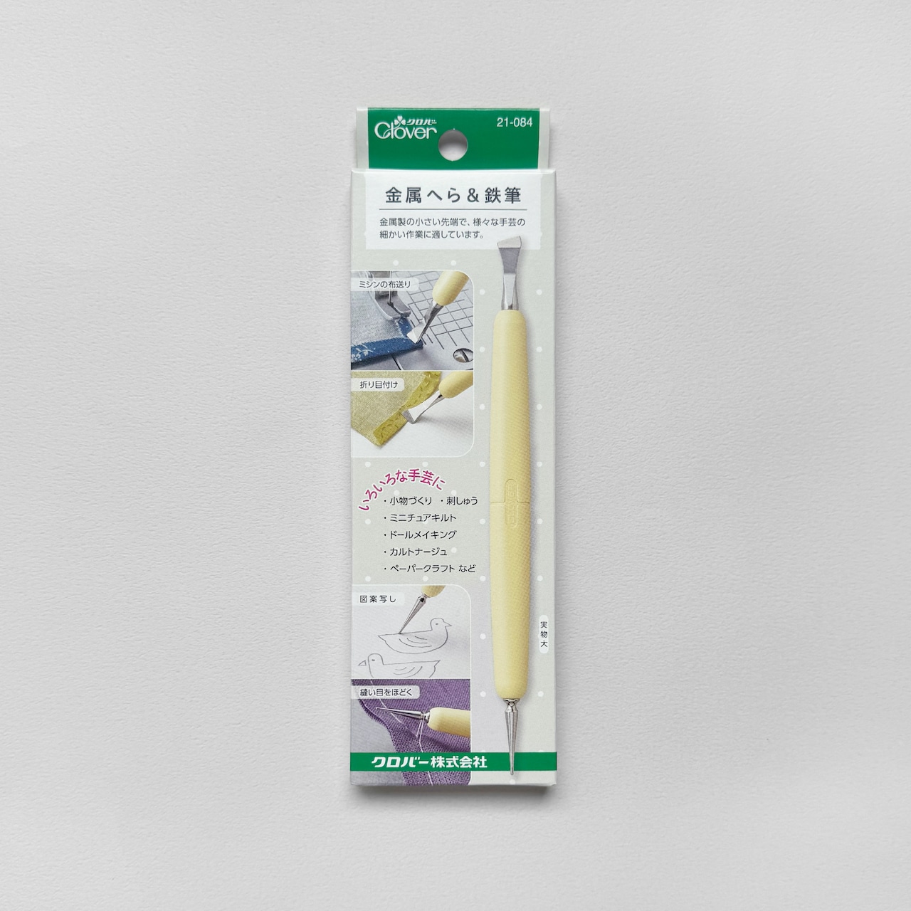 Packaged Clover metal spatula and tracing stylus with yellow handle shown in its retail blister pack on a gray background.