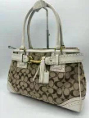 Beige and white Coach signature-pattern canvas tote bag with top handles and tassel charm.