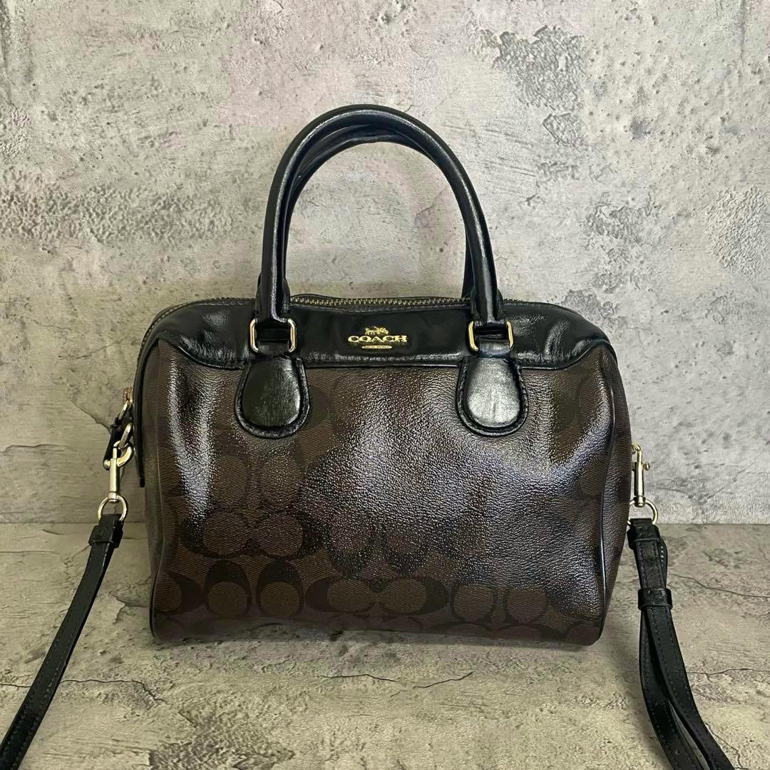 Front view of a black Coach 2-way mini boston shoulder bag with top handles, detachable shoulder strap, and Coach logo on the front.