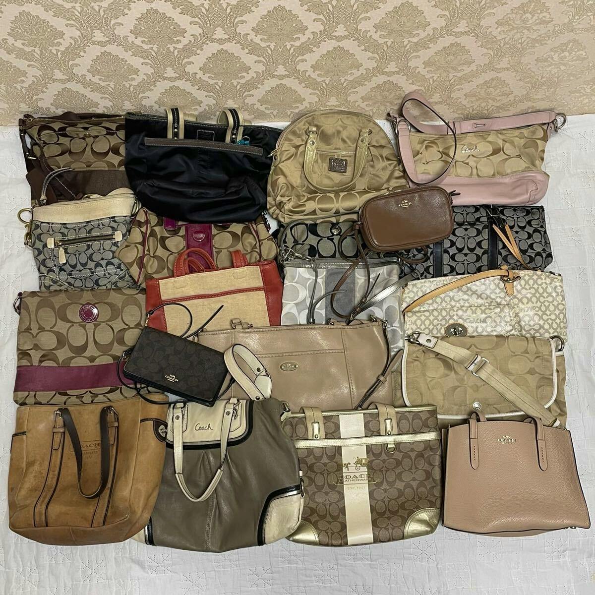 Multiple Coach bags and purses arranged on a flat surface showing a variety of styles and colors.
