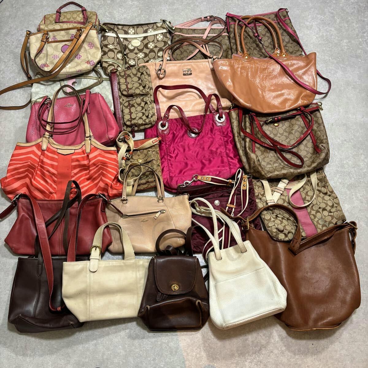 Multiple Coach handbags and totes in various colors and materials laid out flat on a surface, showing a lot/bundle of bags.