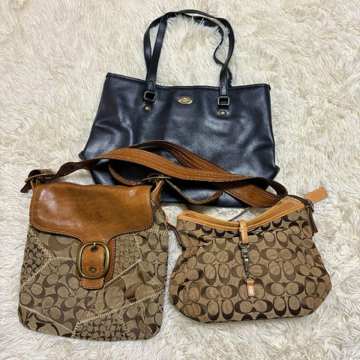 Three COACH bags: a black leather tote and two brown signature canvas shoulder bags laid on a light rug.