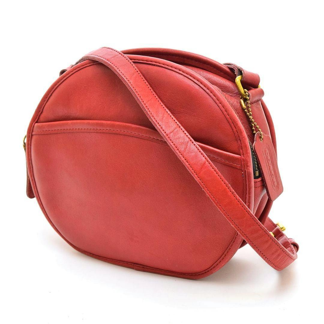 Red round Coach leather mini shoulder bag with shoulder strap and hanging leather tag.
