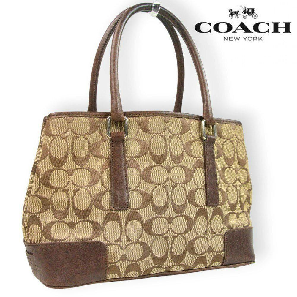 Front view of a beige and brown COACH canvas tote bag with leather handles and corner trim showing the signature 'C' pattern.