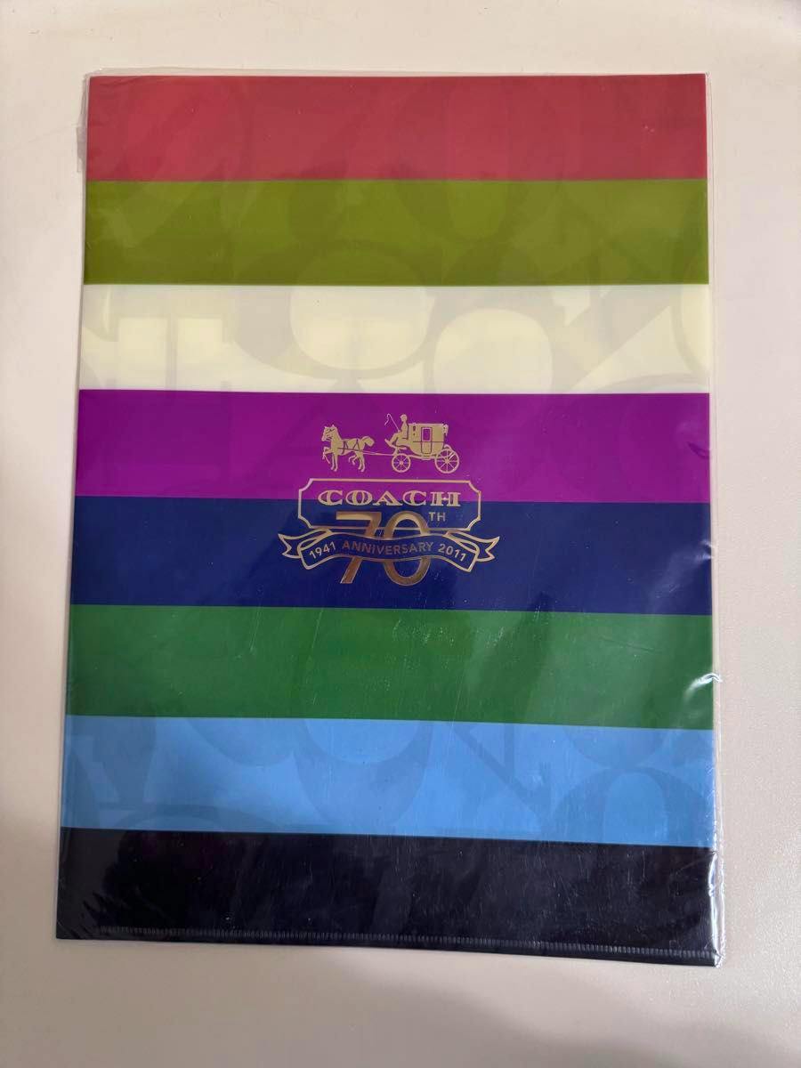 A multicolored striped clear file folder featuring a gold COACH 70th anniversary carriage logo in the center.