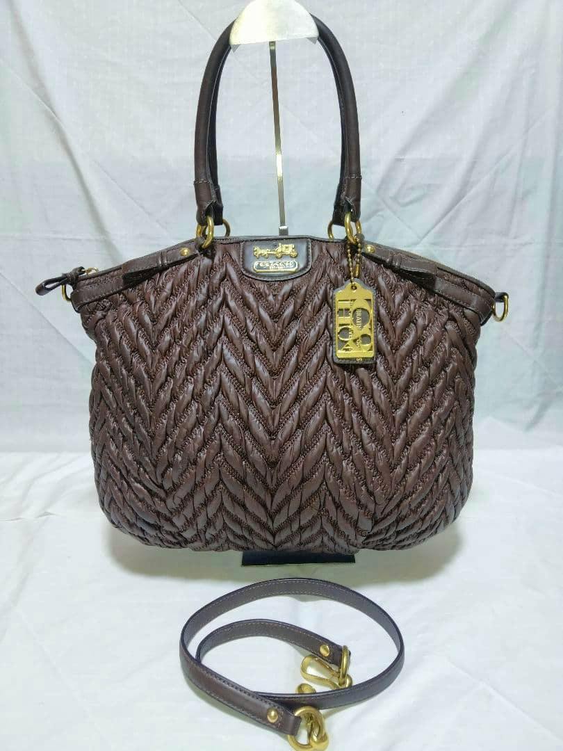 Brown Coach leather shoulder bag with chevron quilted pattern and gold hardware, shown with a detached shoulder strap on a white background.