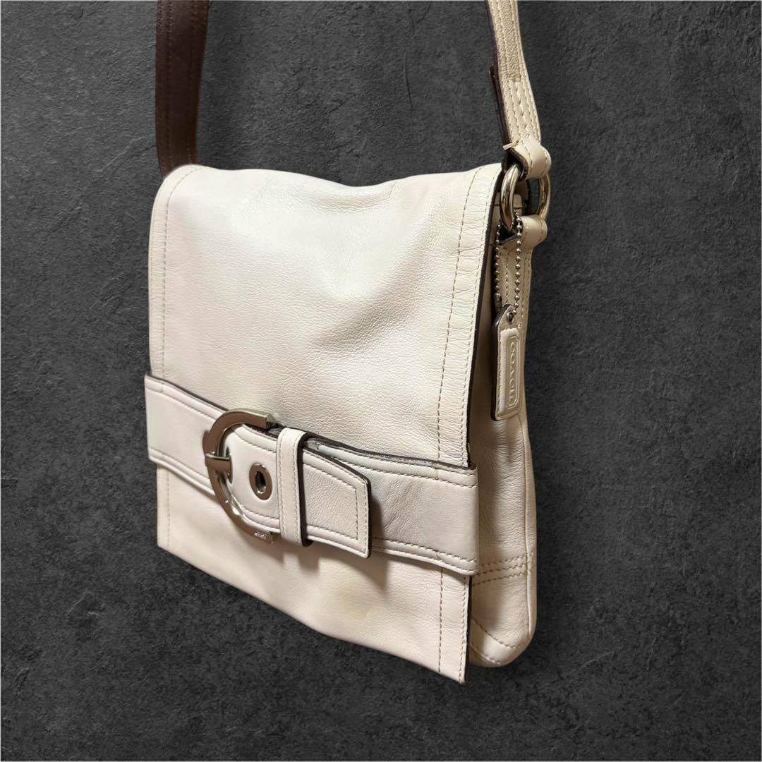 White leather shoulder crossbody bag showing the front flap with a wide belt-like buckle detail and leather shoulder strap.
