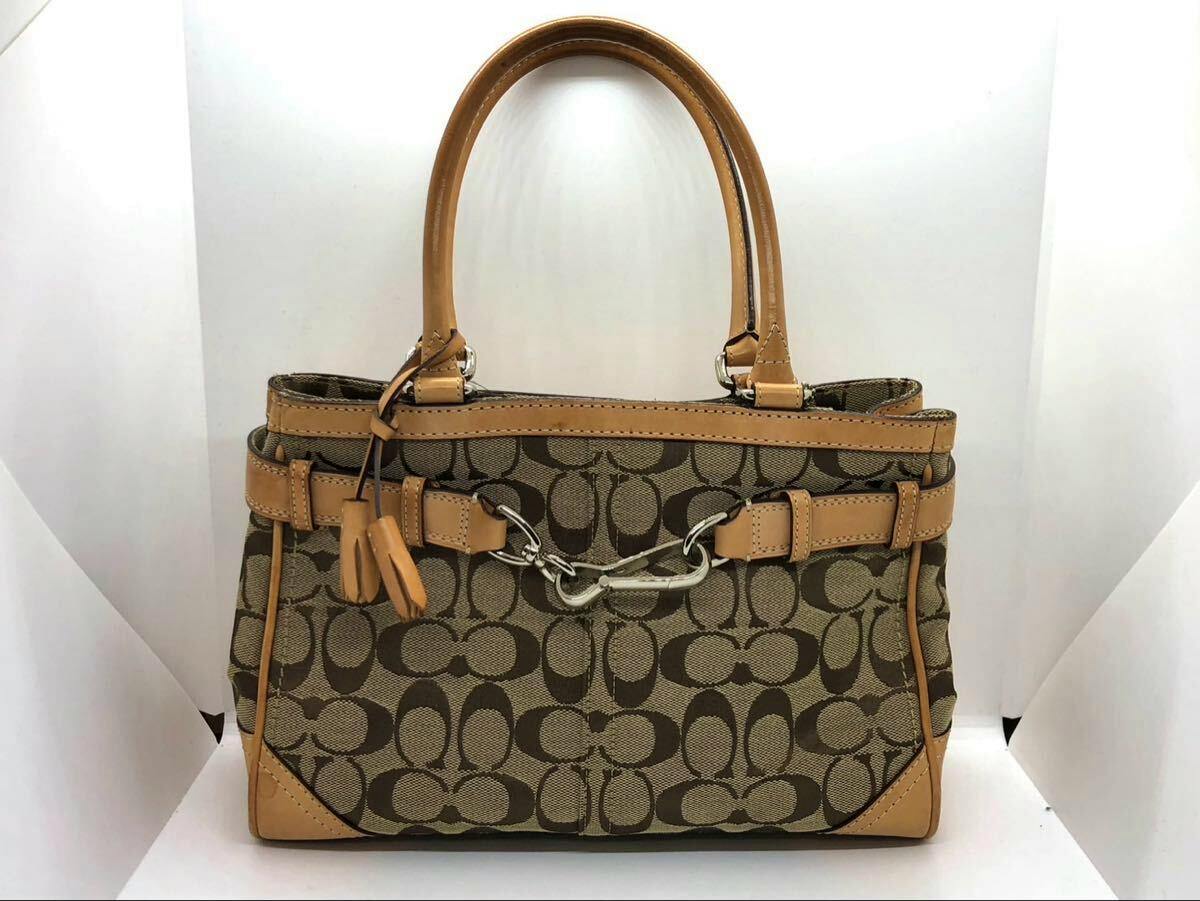 Front view of a COACH signature canvas and leather tote bag with double handles and metal hardware.