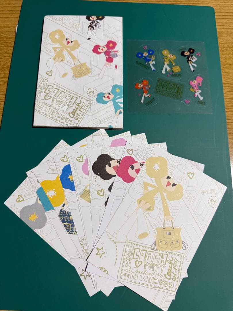 COACH A5 letter papers fanned out with a matching sticker sheet on a green surface.