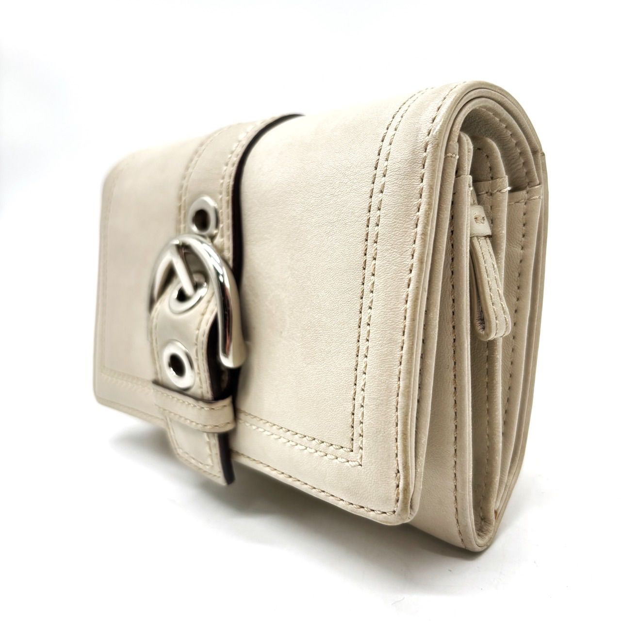All-white COACH compact cow leather bi-fold wallet shown at a front-side angle with buckle hardware.