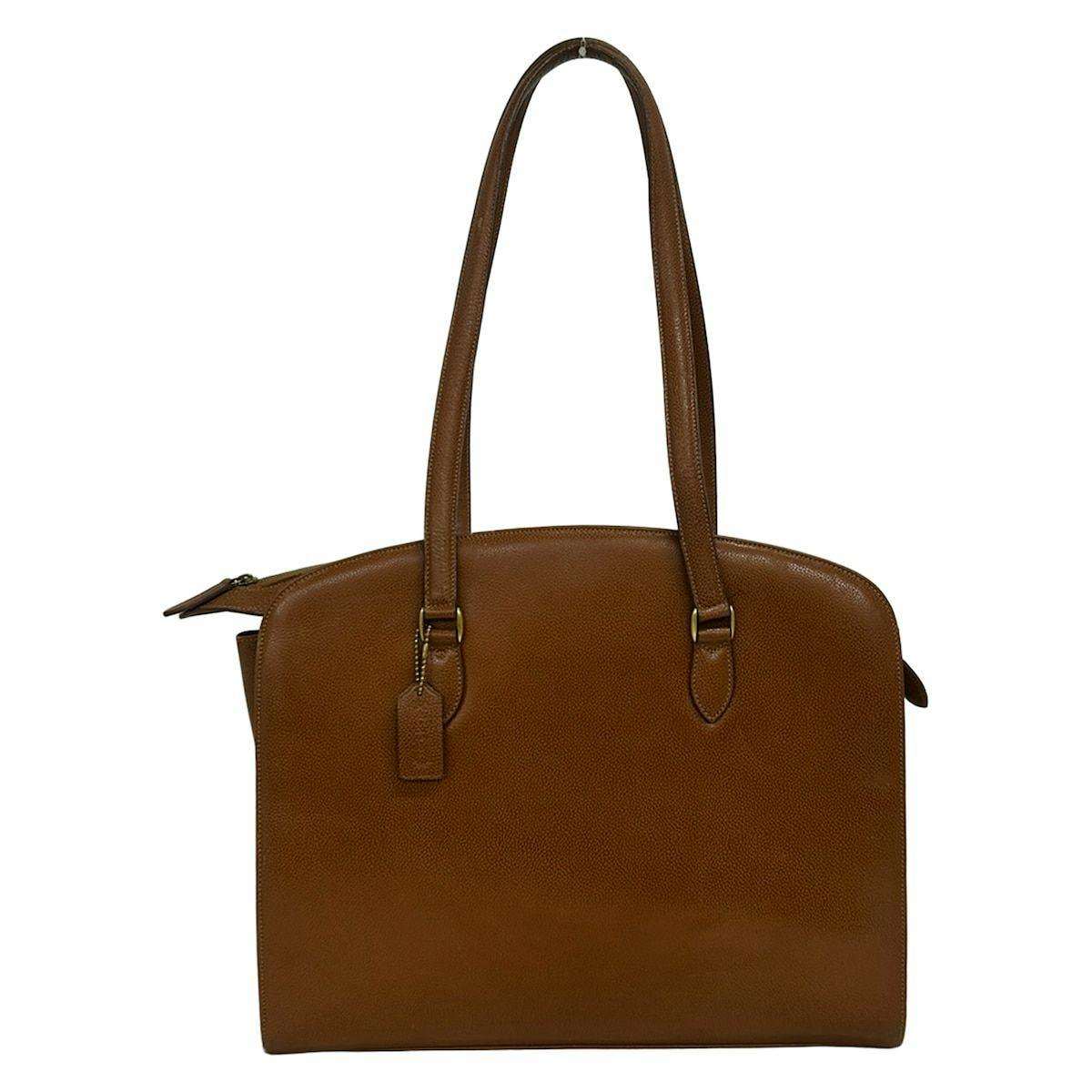 Front view of a brown leather COACH Arcadia tote bag with double shoulder straps and a leather hangtag.