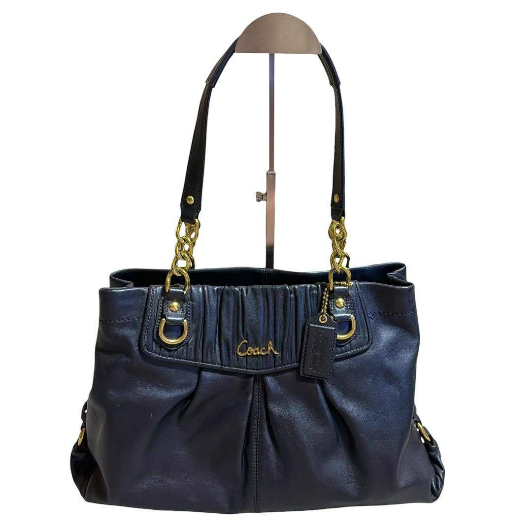 Front view of a black Coach Ashley gathered cow leather satchel with gold hardware, Coach logo, and double-chain shoulder straps.