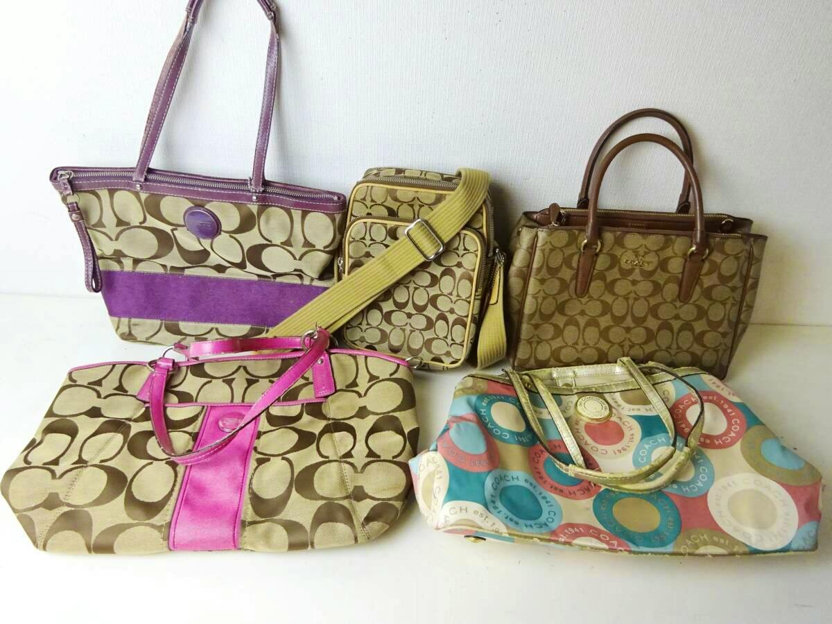 Five COACH canvas bags of various styles and colors arranged on a white surface, showing the front views of each bag.