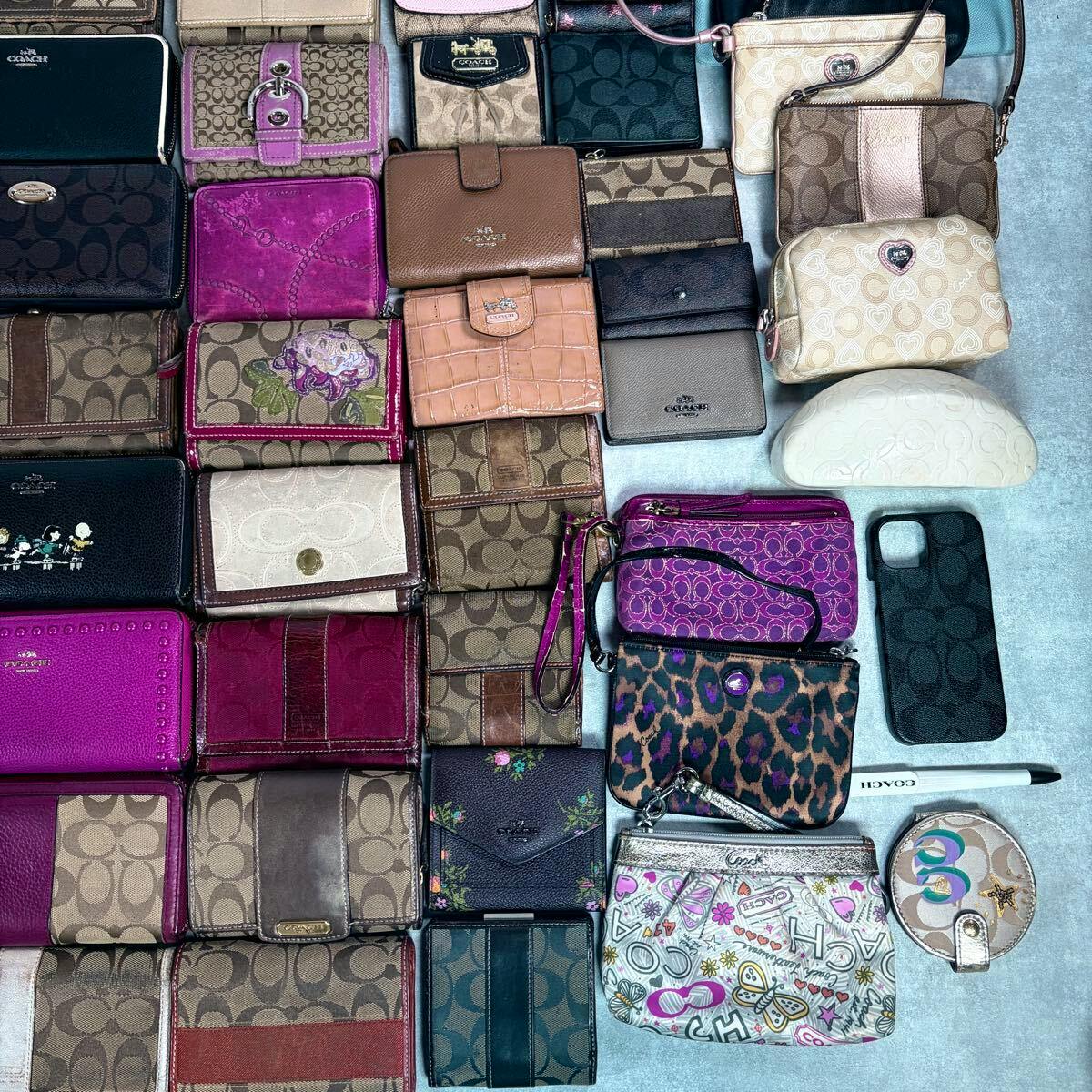 Overhead photo showing numerous Coach wallets, small pouches, and accessories arranged on a flat surface.