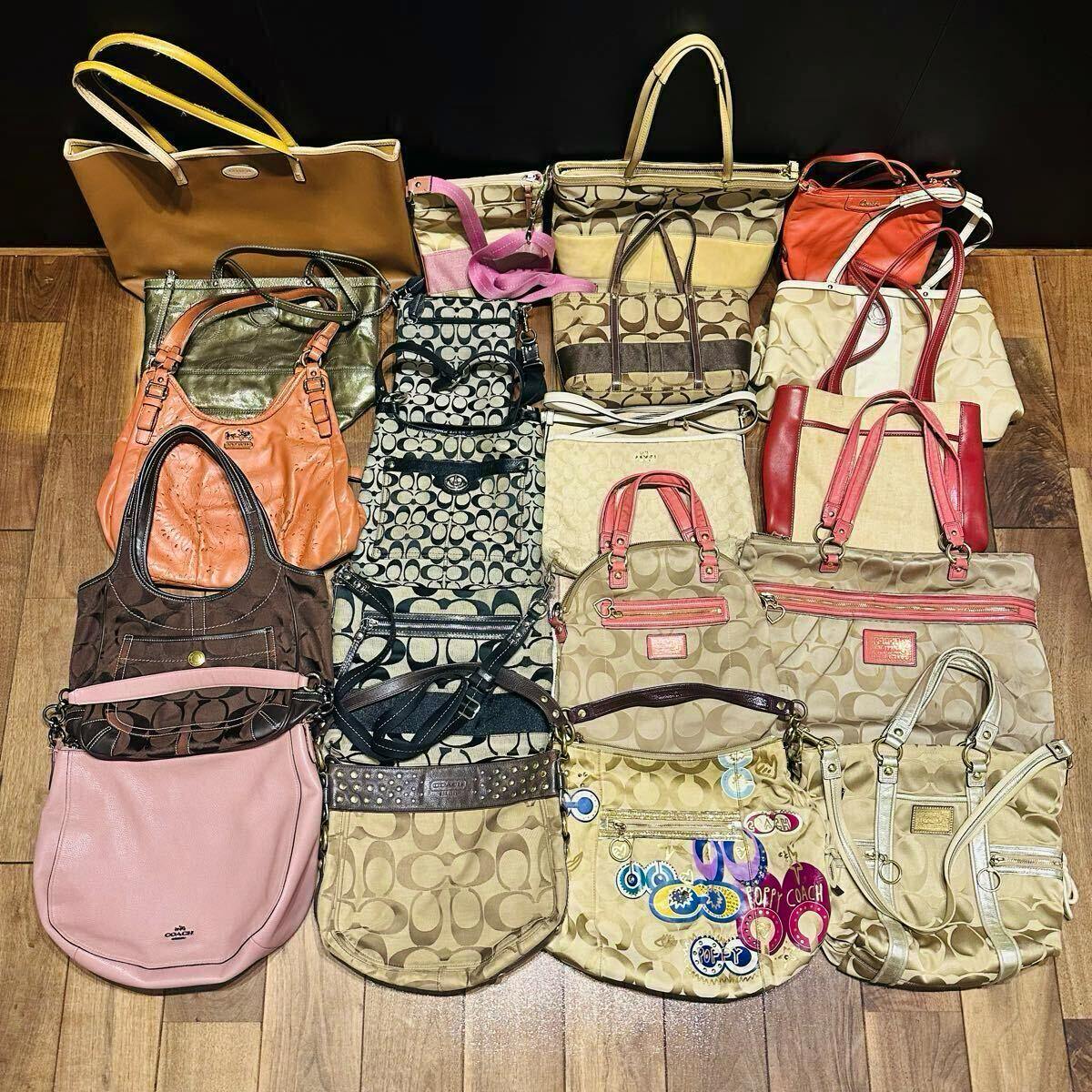Top-down photo of a set of COACH bags and purses arranged on a wooden floor showing various signature C patterns, colors, and styles.