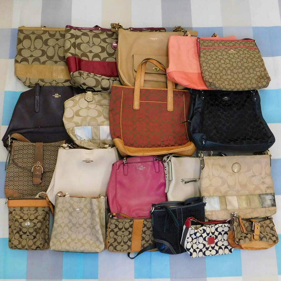 A grouped assortment of Coach handbags and small bags laid out showing various signature patterns and colors.
