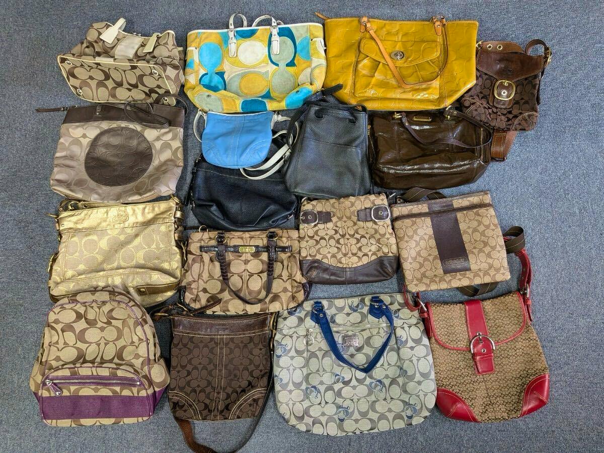 Multiple COACH bags and purses in various styles and colors laid out on a carpeted floor.