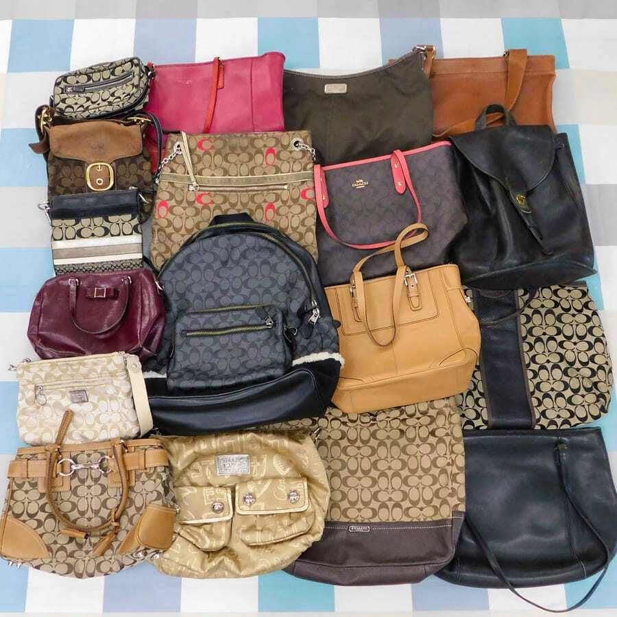 A group of Coach bags and purses in various styles and colors laid out on a checkered surface.