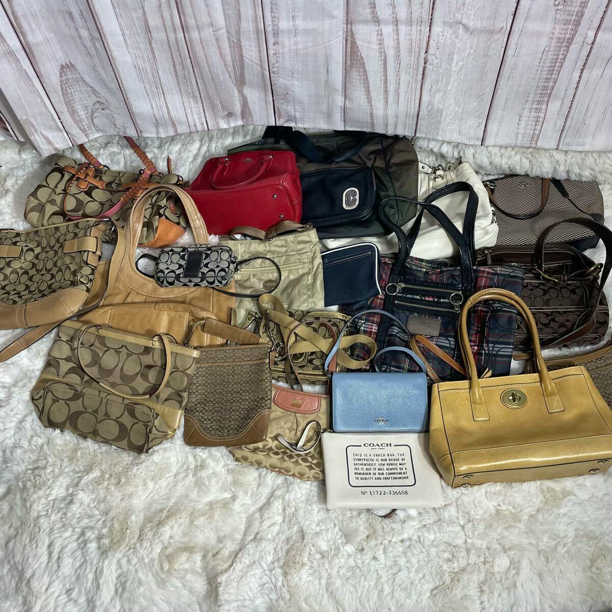 Several Coach handbags and small leather bags arranged together on a white furry surface with a wooden backdrop.