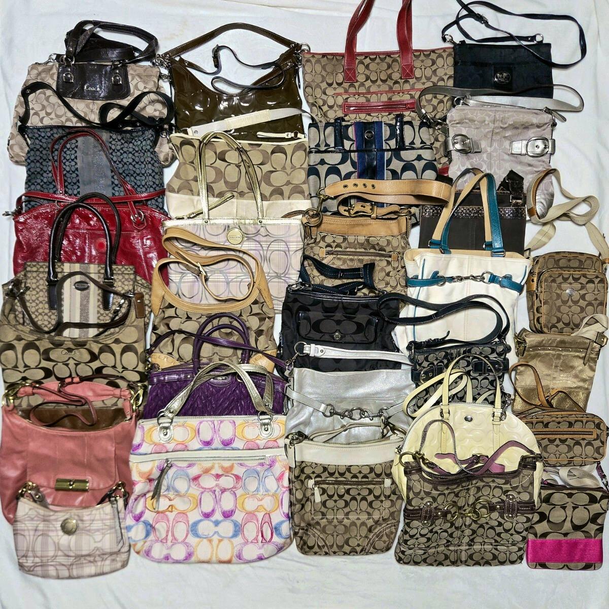 Flat lay of many Coach handbags and shoulder bags in signature canvas patterns arranged on a white background.