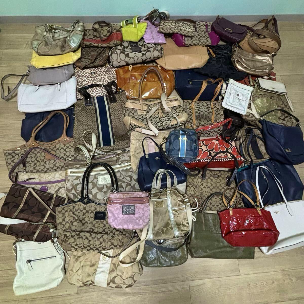 A large assortment of COACH bags in various styles and colors laid out on a floor as a lot.