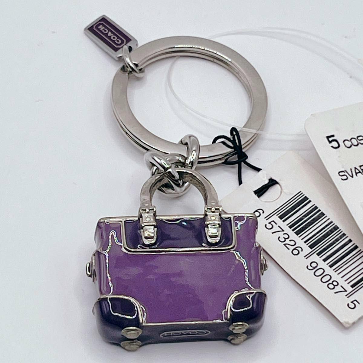 Purple Coach bag-motif keychain charm attached to a metal key ring with barcode tags visible.