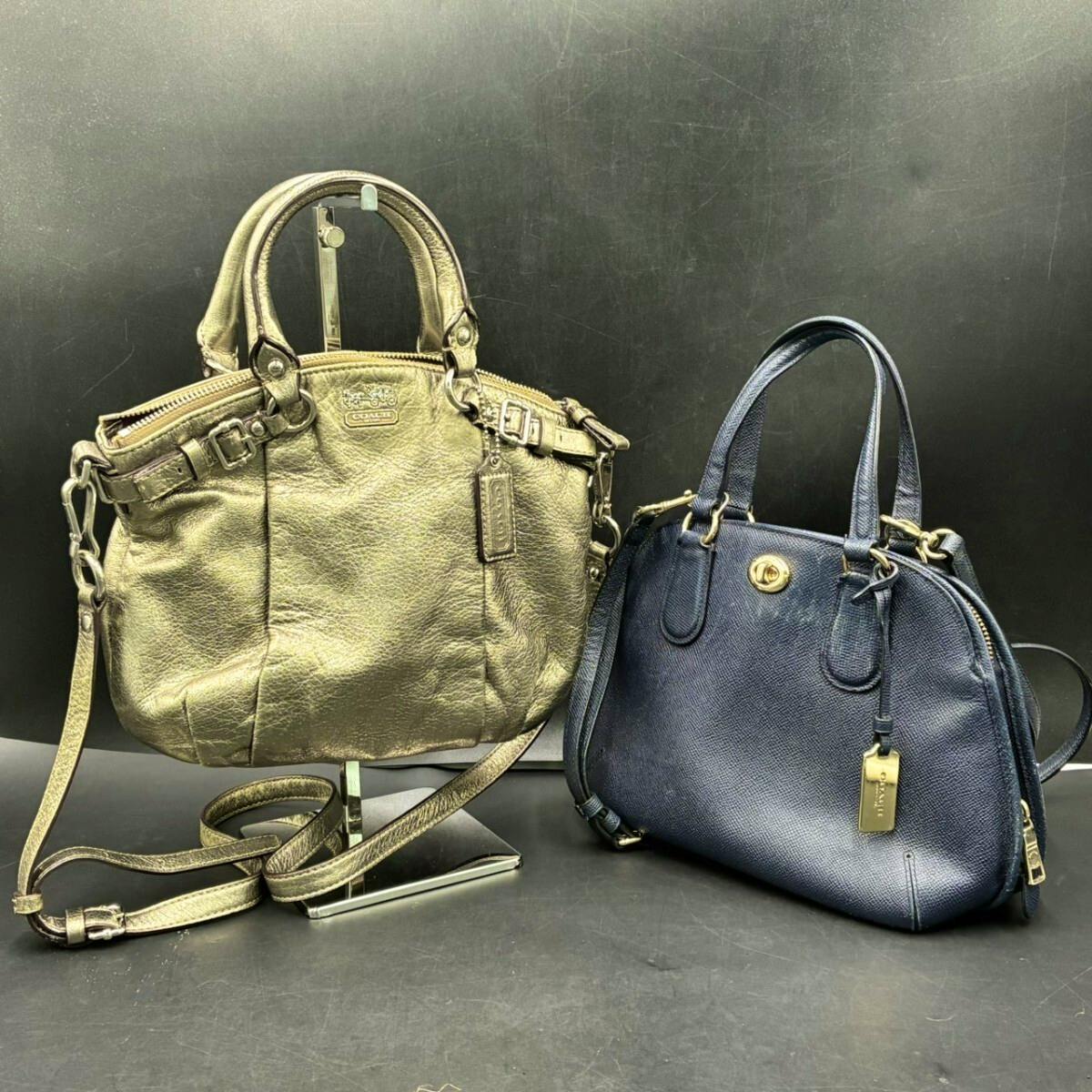 Two COACH bags side by side: a gold-colored shoulder bag on the left and a navy handbag on the right.