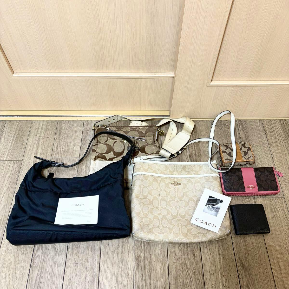 Several COACH bags and wallets arranged on a wooden floor in front of a door, shown as a bulk set.