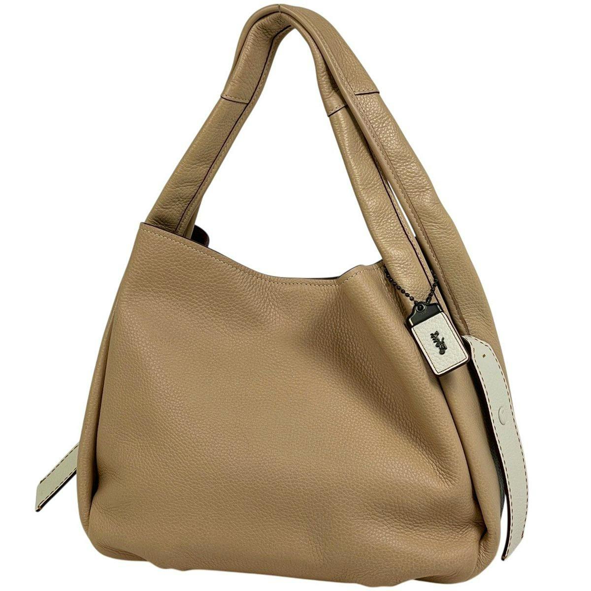 Beige leather Coach Bandit hobo shoulder handbag shown from front with handle and Coach tag visible.