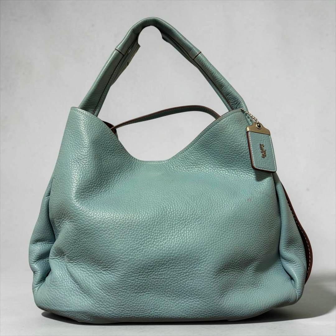 Front view of the light blue Coach Bandit hobo tote bag in cow leather with a hanging Coach tag.