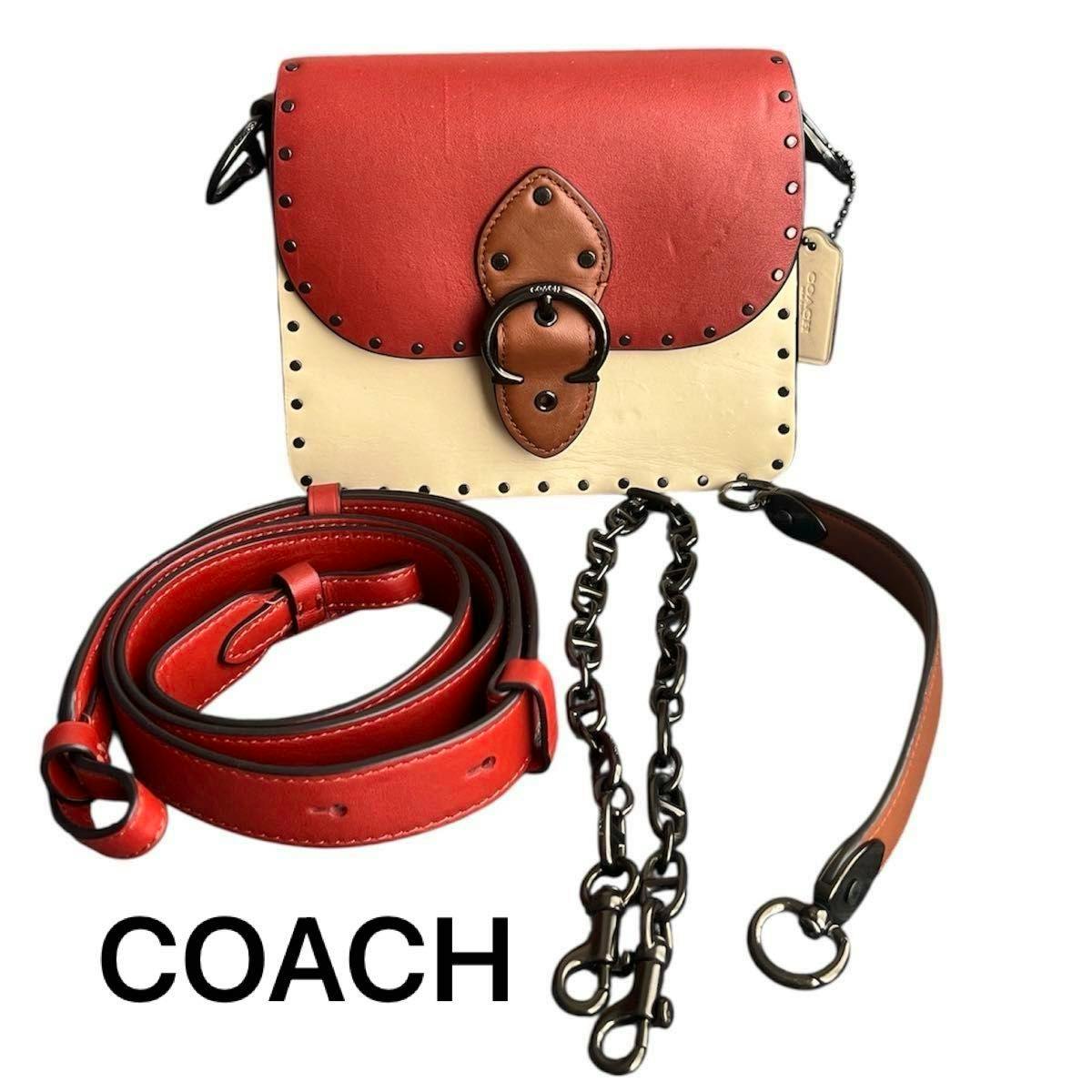 Front view of a small COACH color-block leather shoulder bag with stud detailing, shown with its removable leather strap and chain.