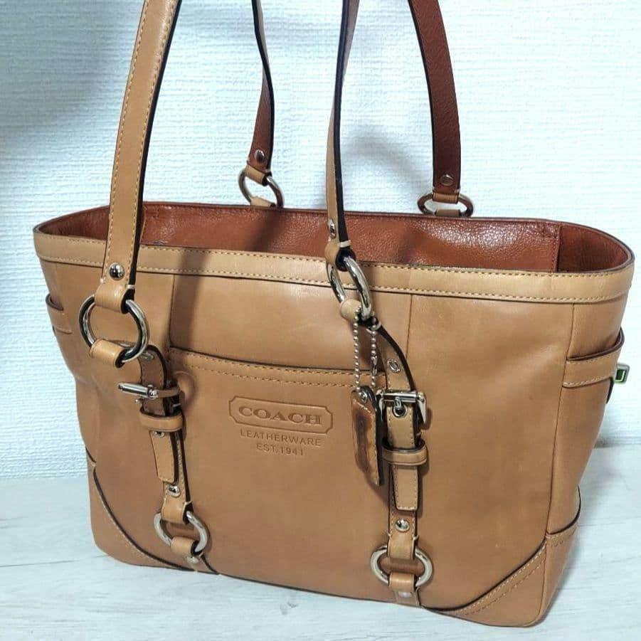 Beige Coach leather A4 tote bag with double shoulder straps and embossed COACH logo on the front.