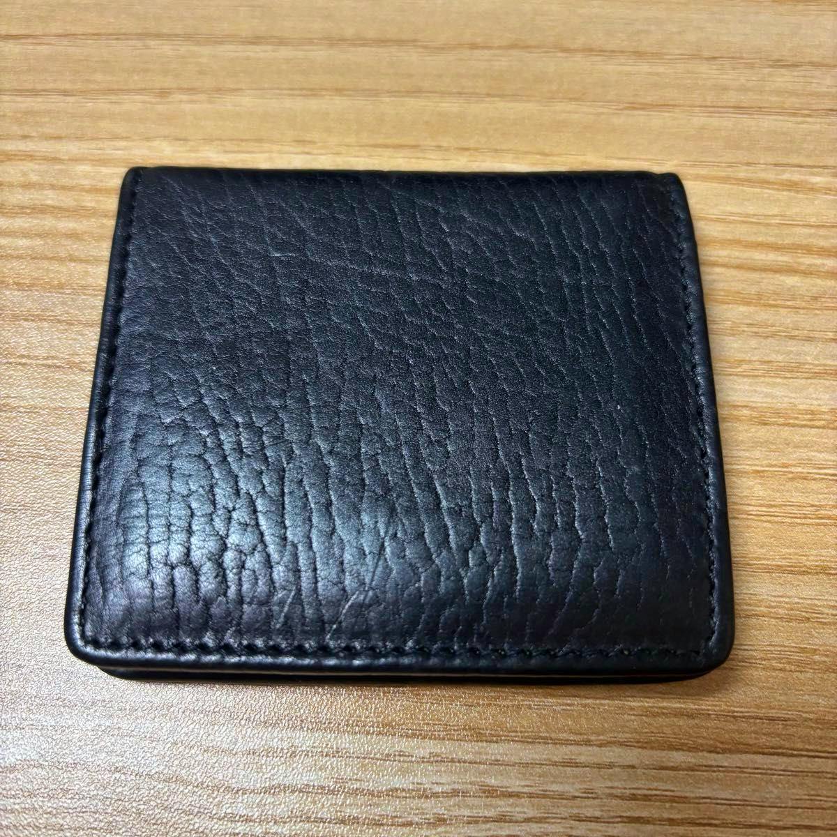 Top-down photo of the black Coach cow leather coin case placed on a wooden surface.