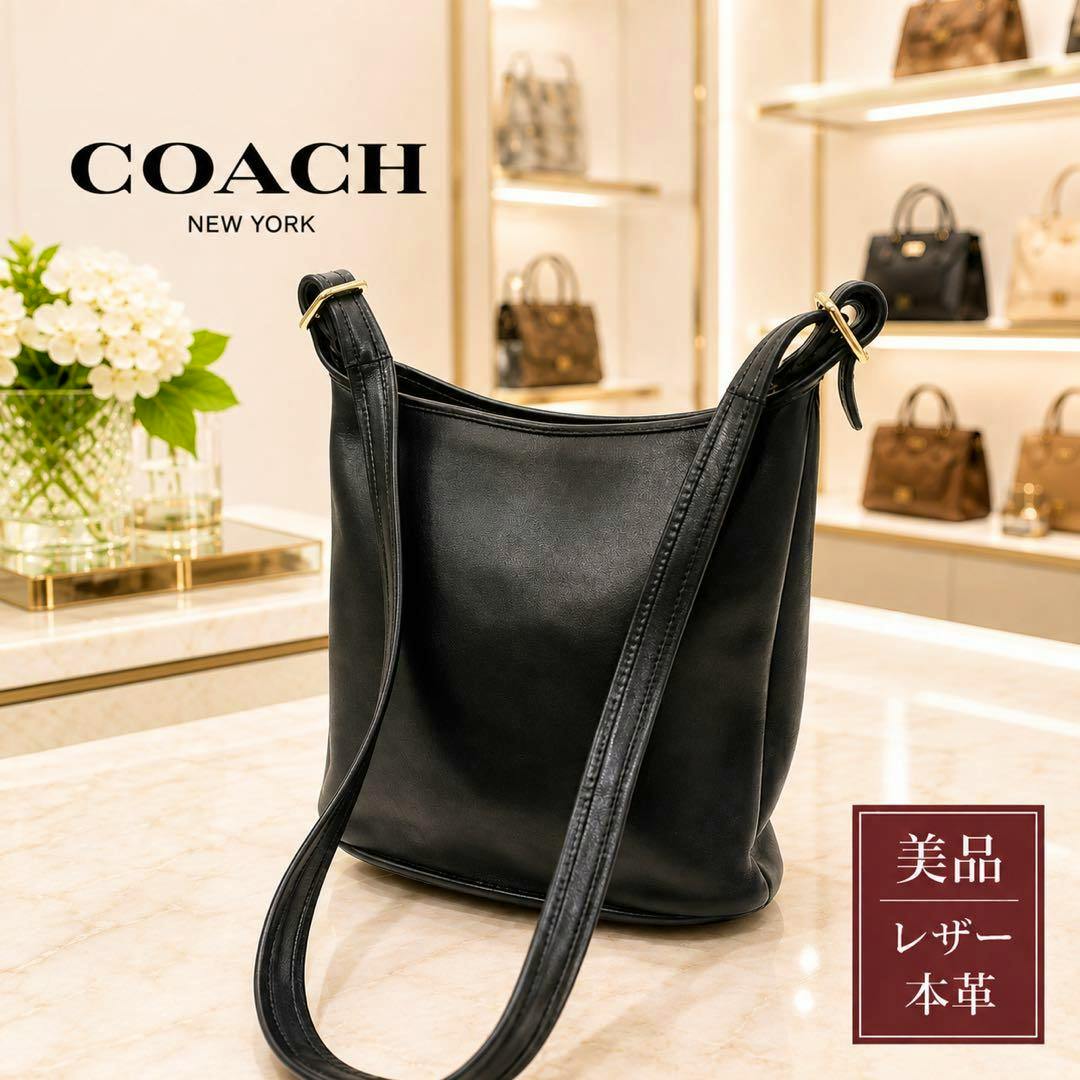 Black COACH leather shoulder bag displayed on a marble countertop in a store setting.