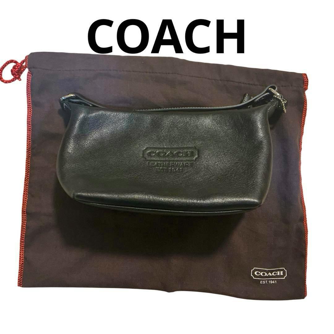 Black Coach leather shoulder bag placed on a Coach dust bag.