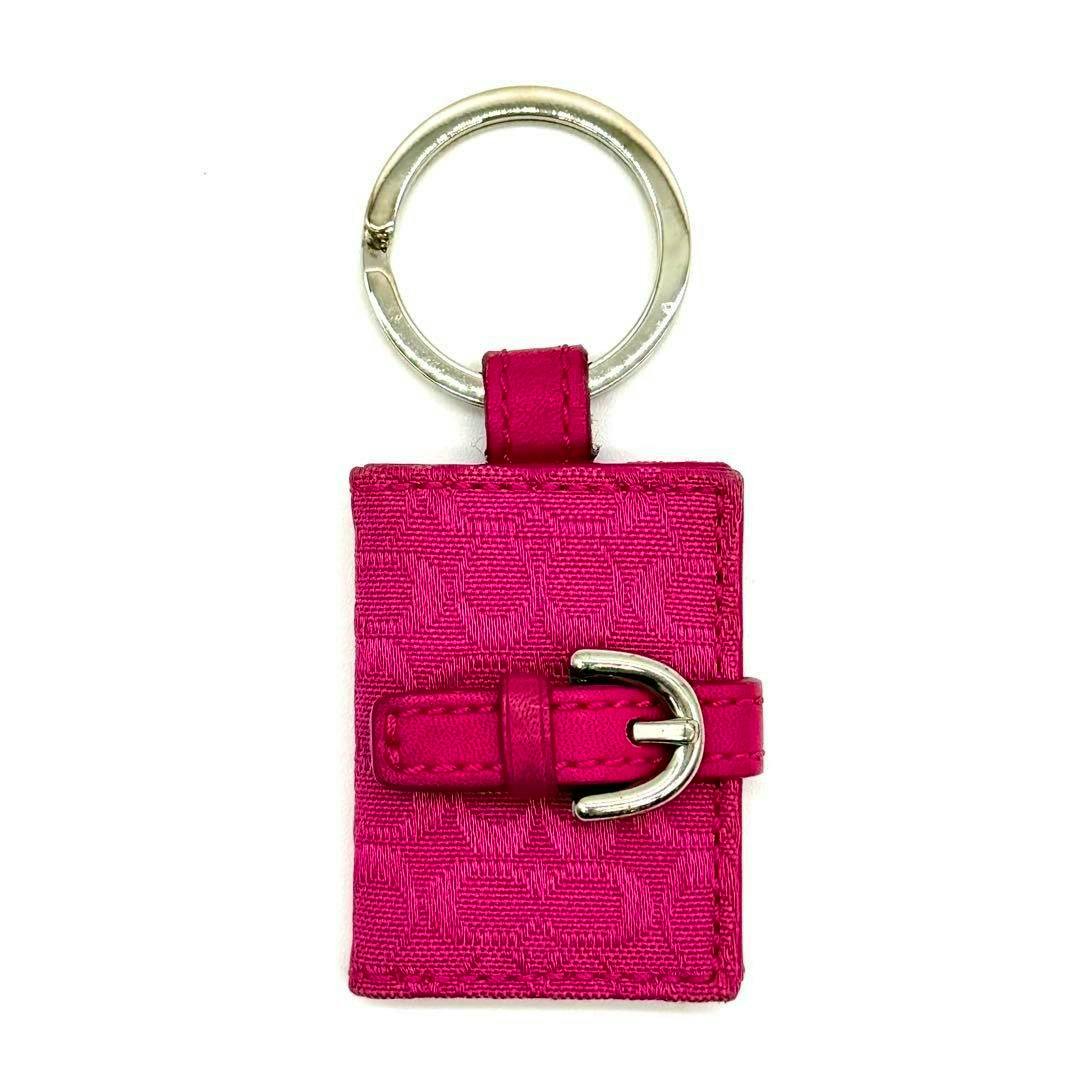 Pink book-shaped Coach photo keychain with a silver key ring and a buckle strap detail.