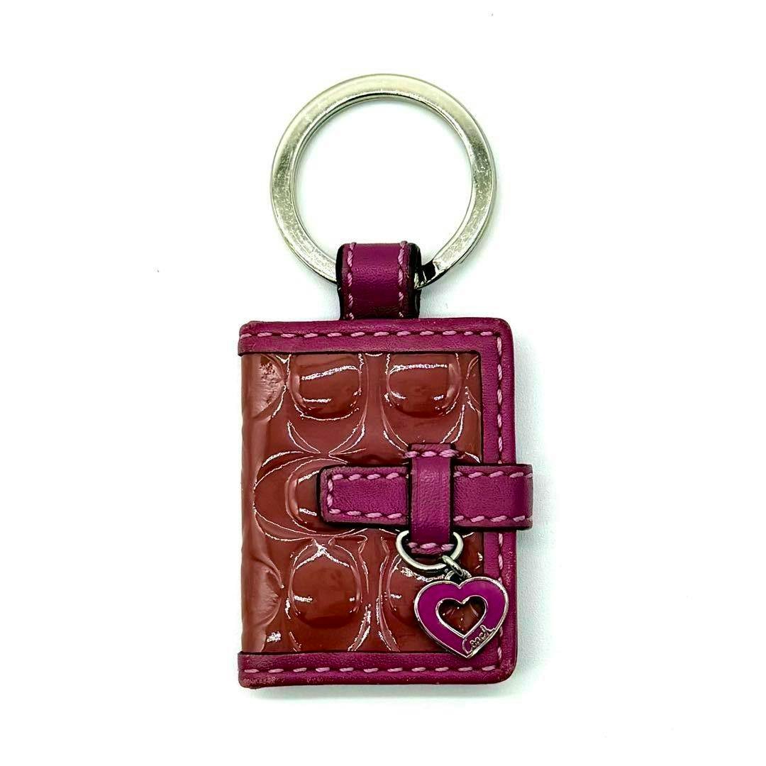 Book-shaped purple Coach photo keychain with a silver key ring and small heart charm on a white background.