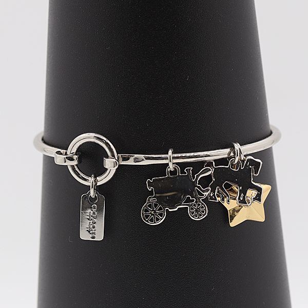 Silver Coach bangle bracelet with carriage, horse, star, and rectangular tag charms displayed on a black cone.