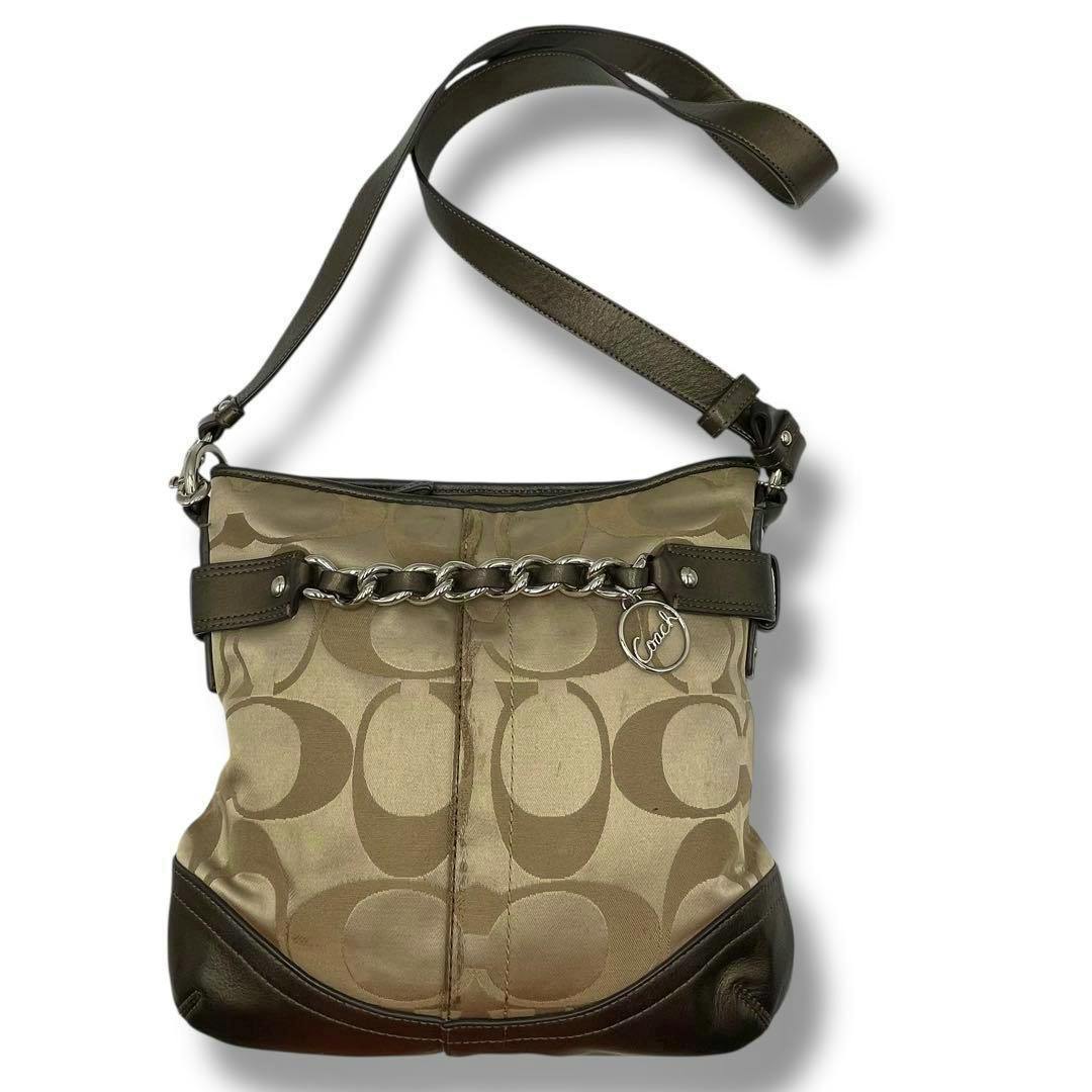 Front view of a brown Coach canvas crossbody shoulder bag with signature C pattern, leather trim, chain accent, and adjustable leather strap.