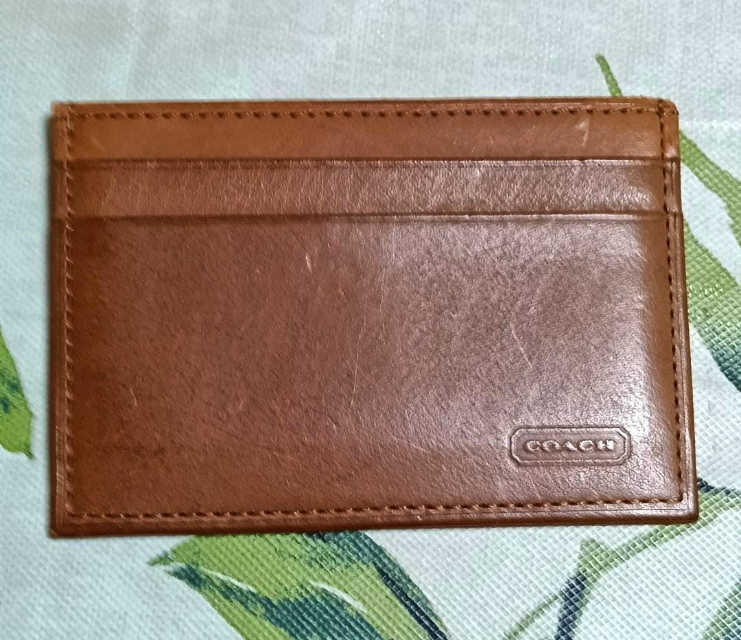 Brown leather card case showing card slots and an embossed COACH logo on the front.